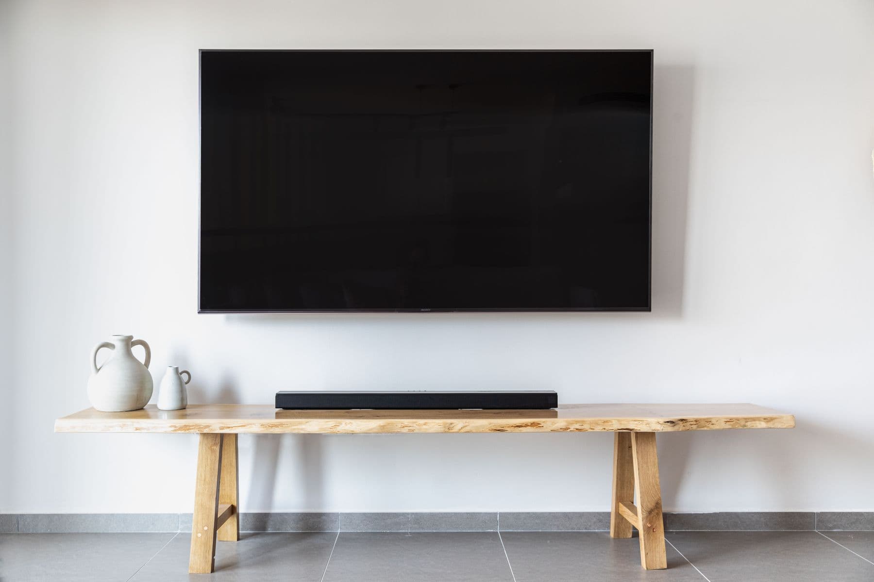 A slim television sitting completely flat against a white wall, resembling framed artwork